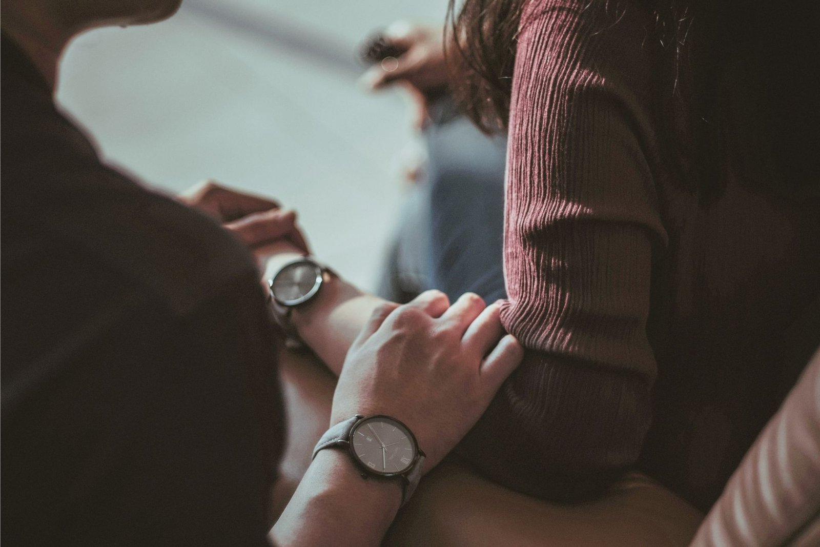 An image of a couple comforting each other. The man has laid his hand on his partner's arm. You can't see their faces.
